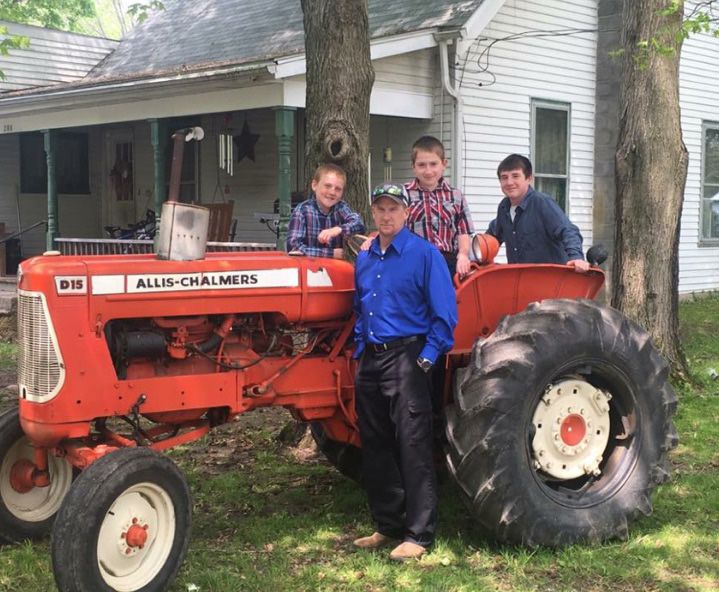 Roy's son (standing) Brent Dick and grandsons (from left) Braxton, Cole and Mason, on the day of the funeral. In honor of their loved one, they drove the tractor behind the hearse to the cemetery.