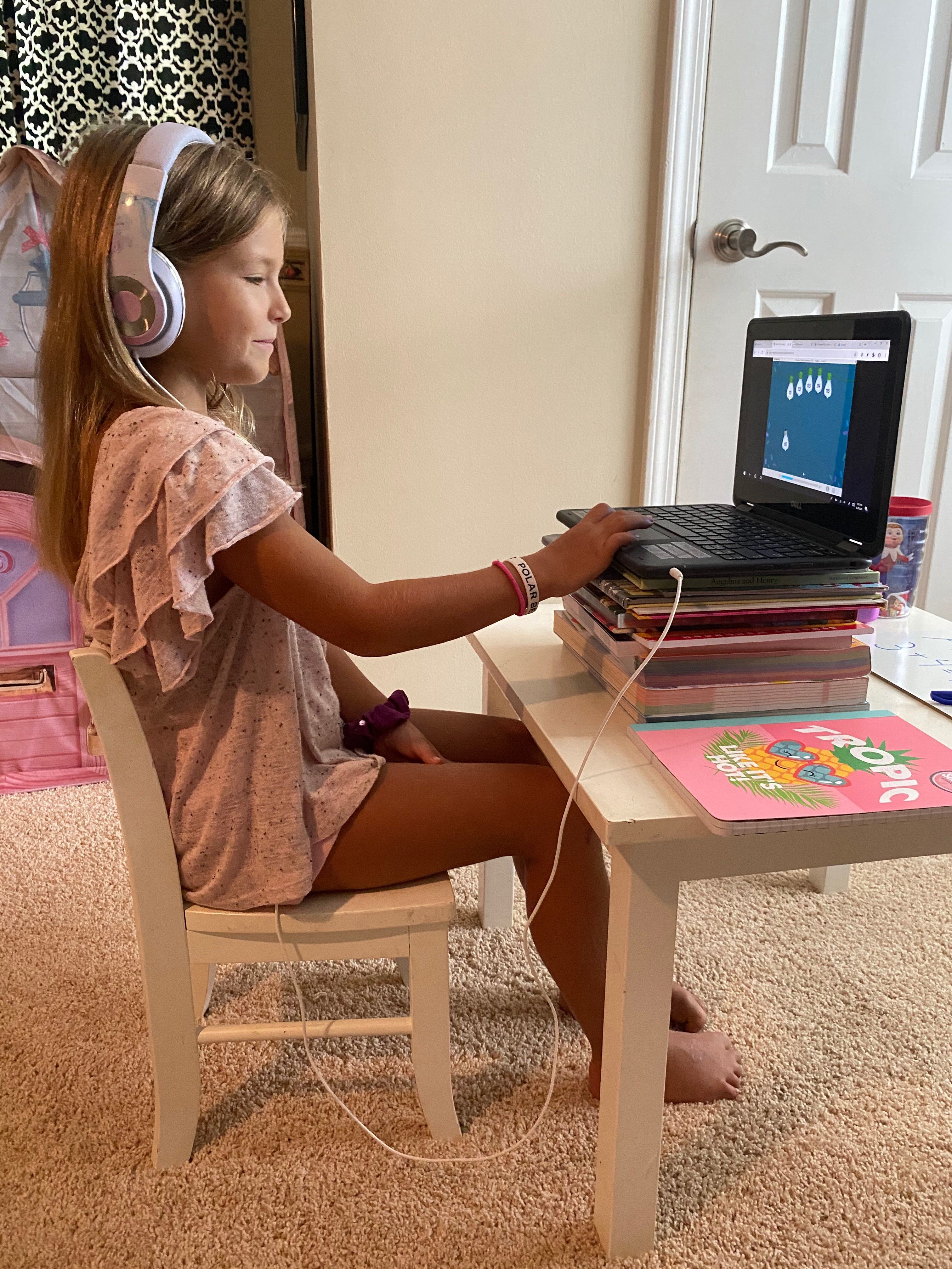 A young female student attends virtual class on her laptop.