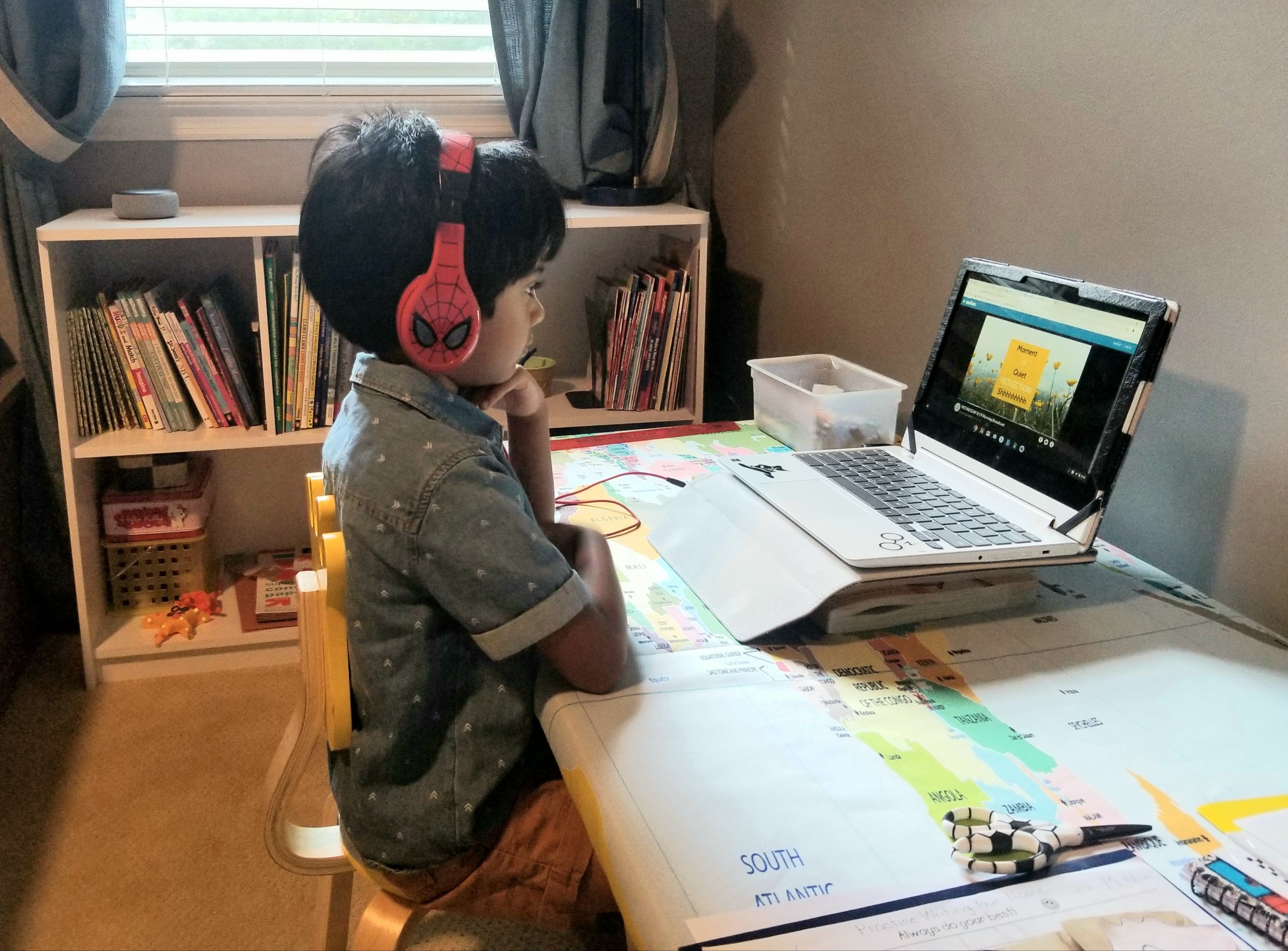 A young male student attends virtual class on his laptop.