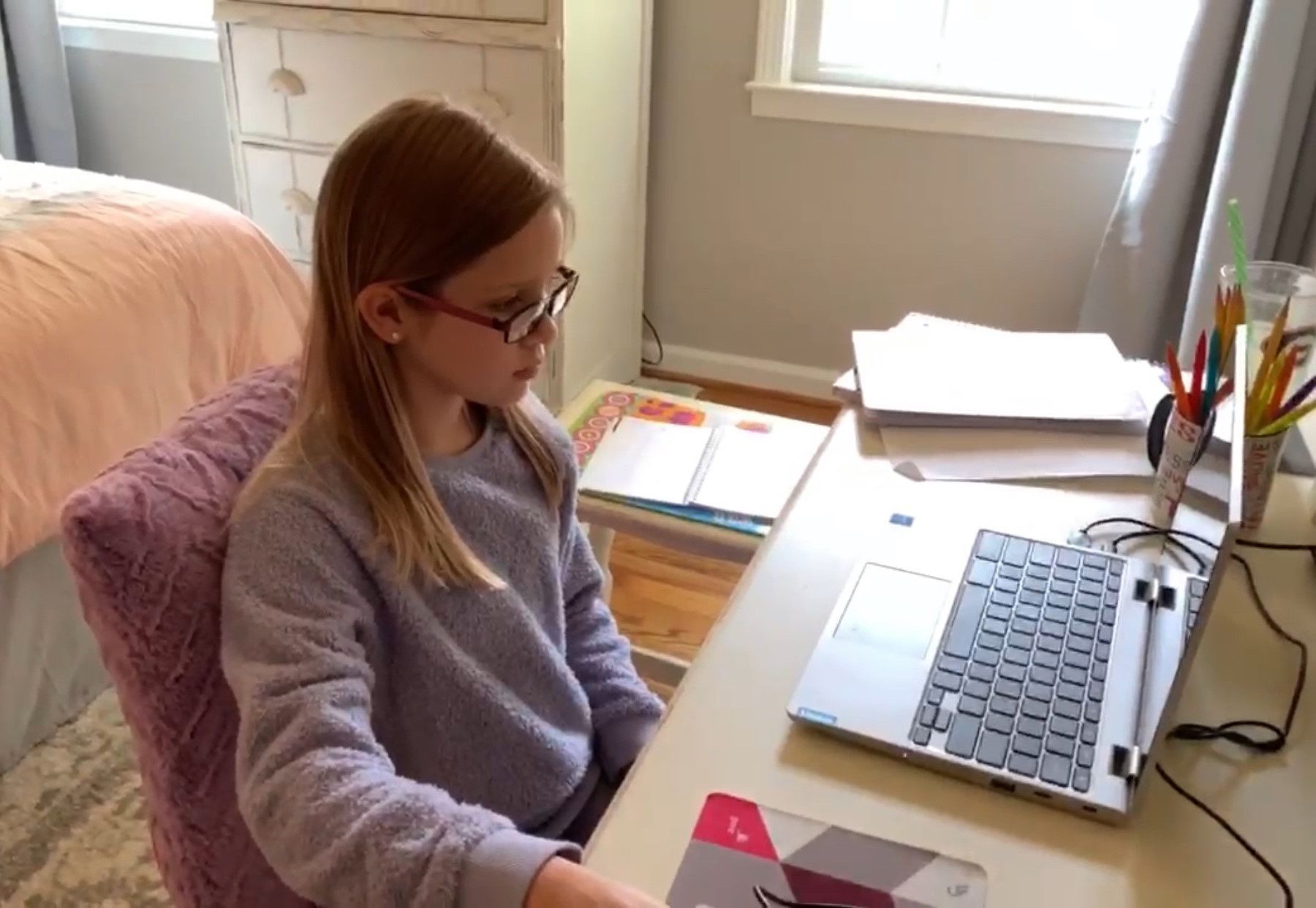 A young female student attends virtual class on her laptop.