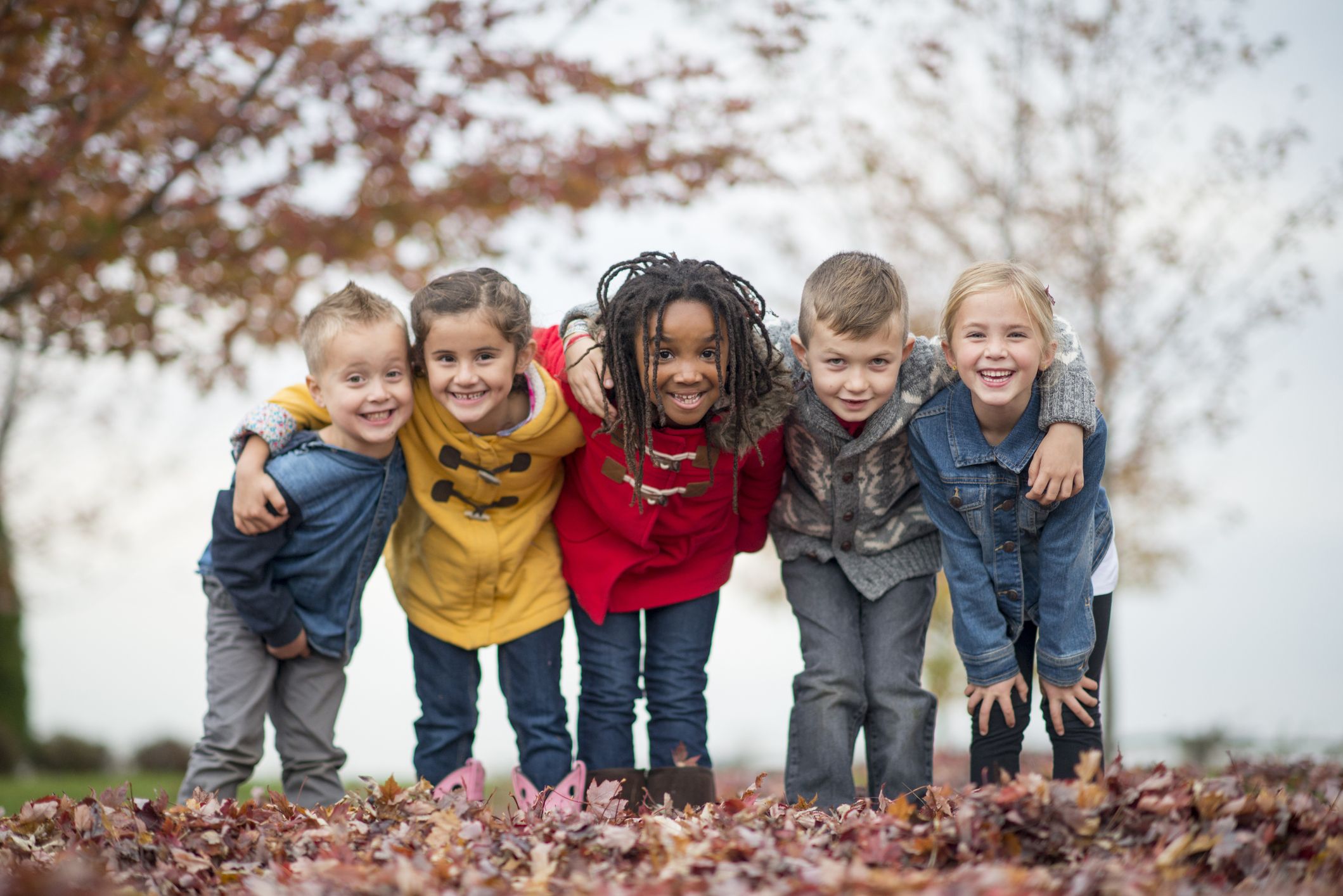 A group of five children pose outdoors.