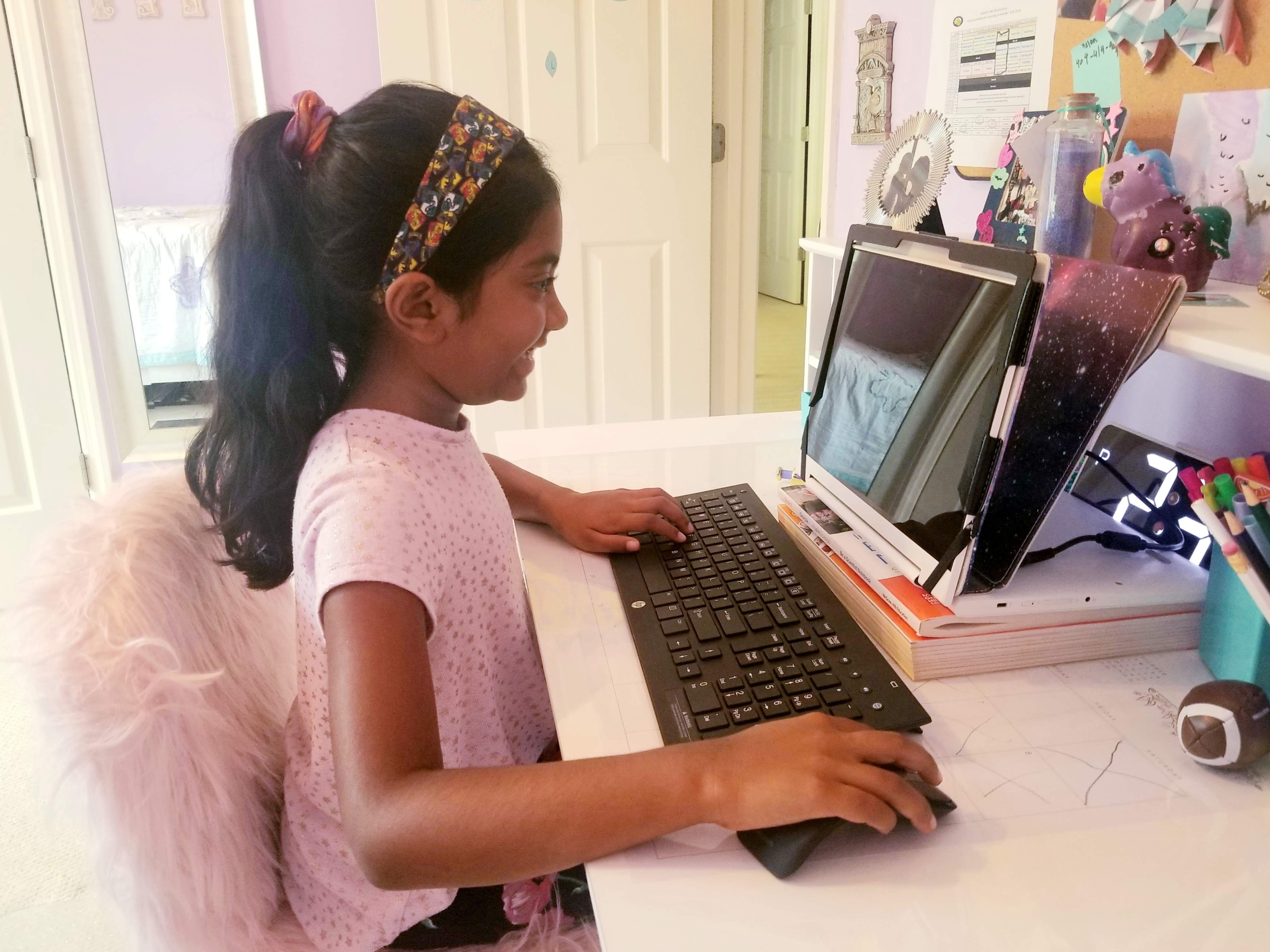 A young female student attends virtual class on her laptop.