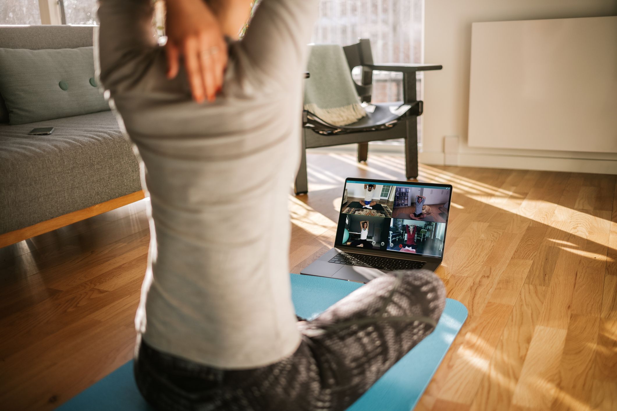 A woman stretches while attending a virtual yoga class.
