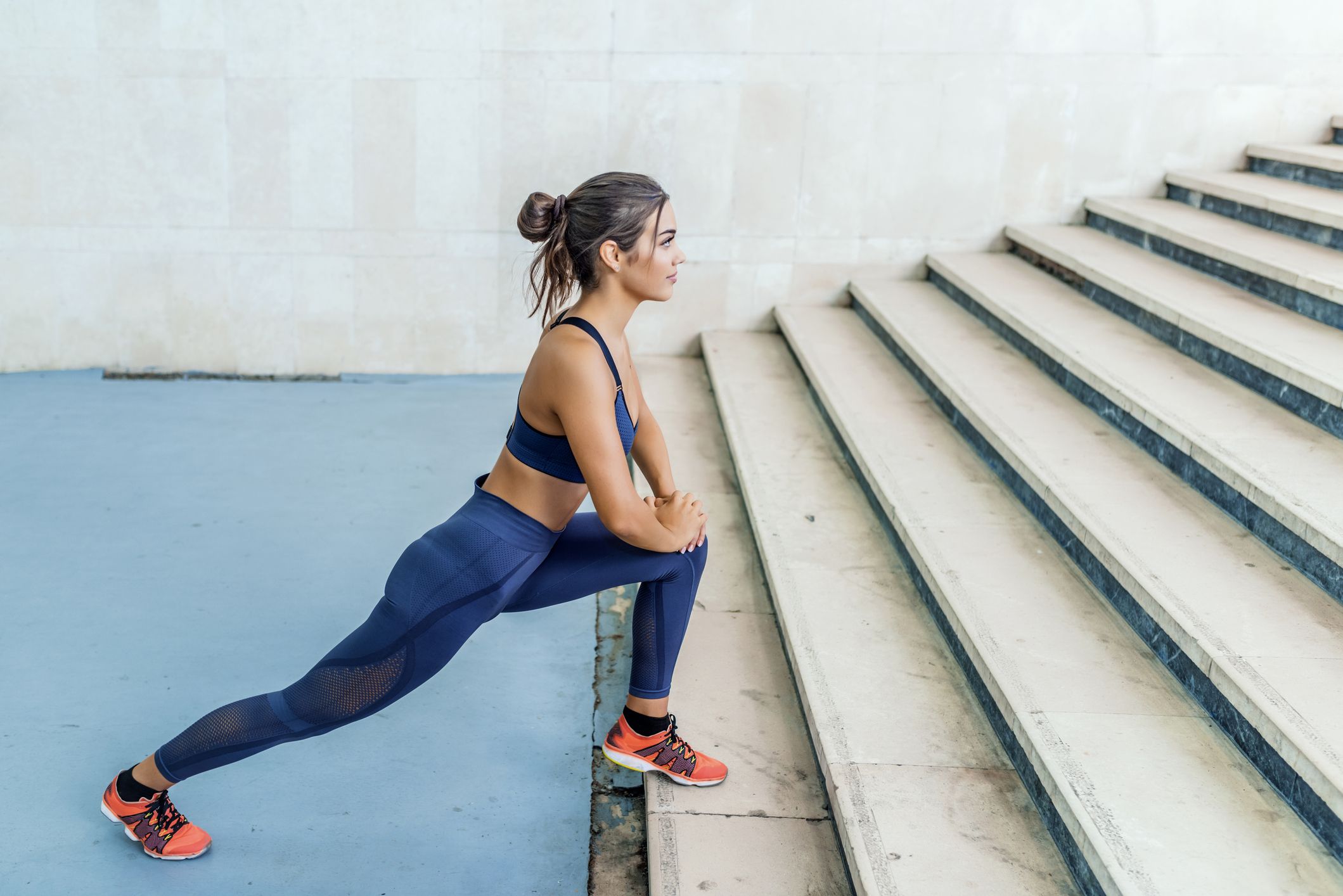 A female runner stretches at the bottom of an outdoor staircase.