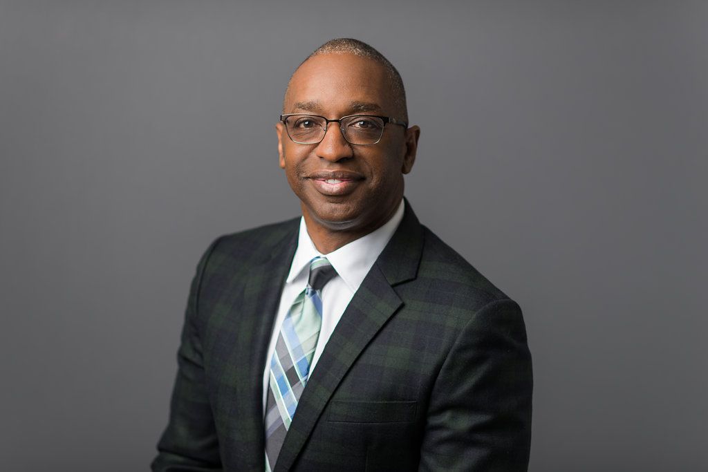 Dr. Erroll Bailey poses in front of a gray backdrop.