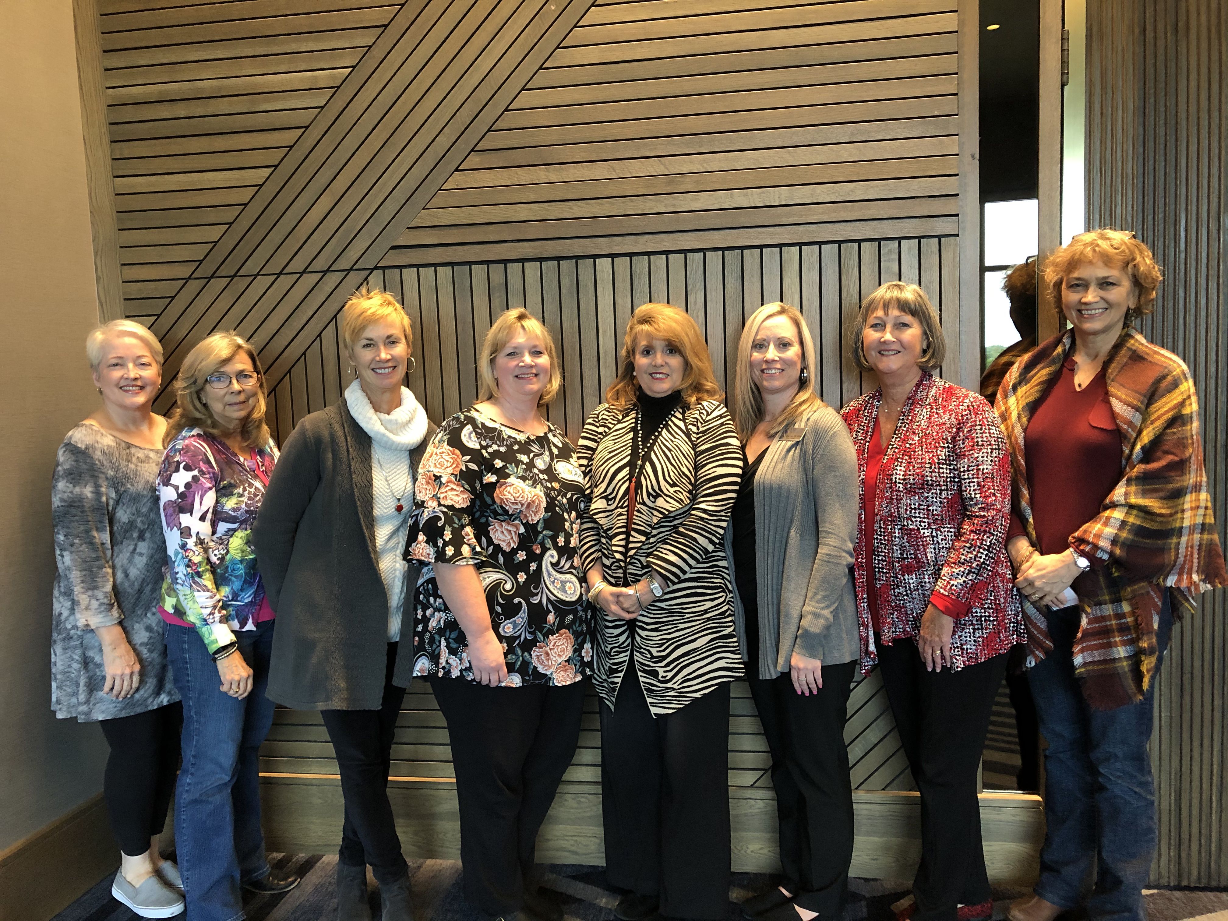 A group of Resurgens nurses pose in front of a wooden wall.