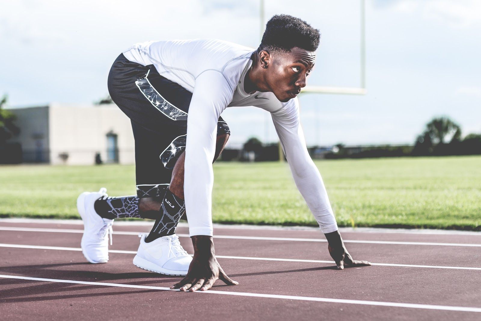 A sprinter waits in the ready position on the track to begin their race.