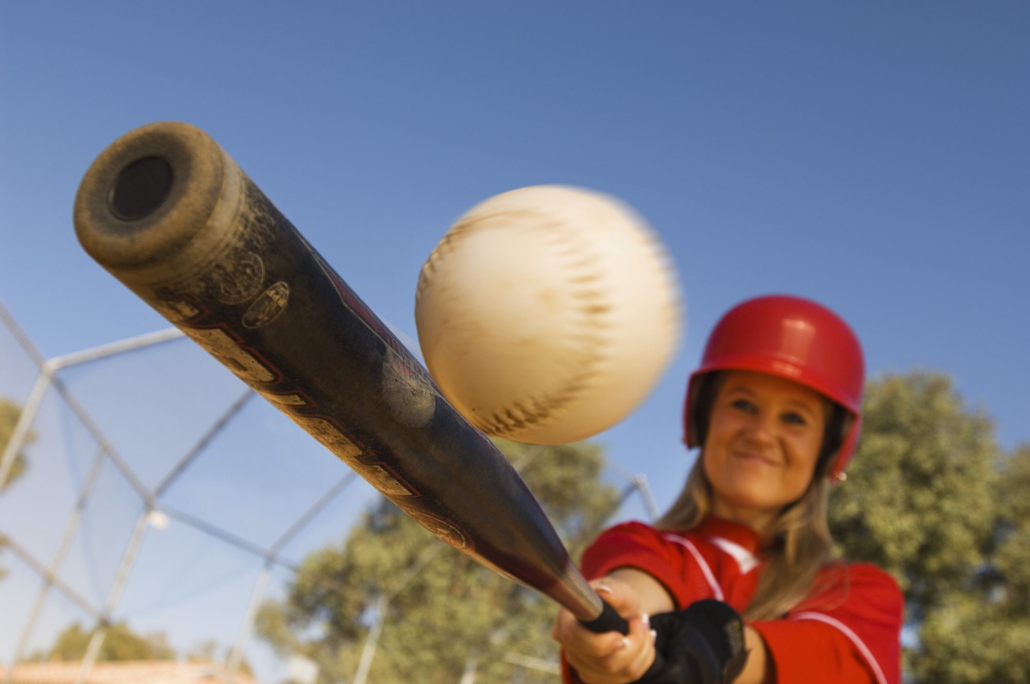 A softball batter makes contact with the ball.