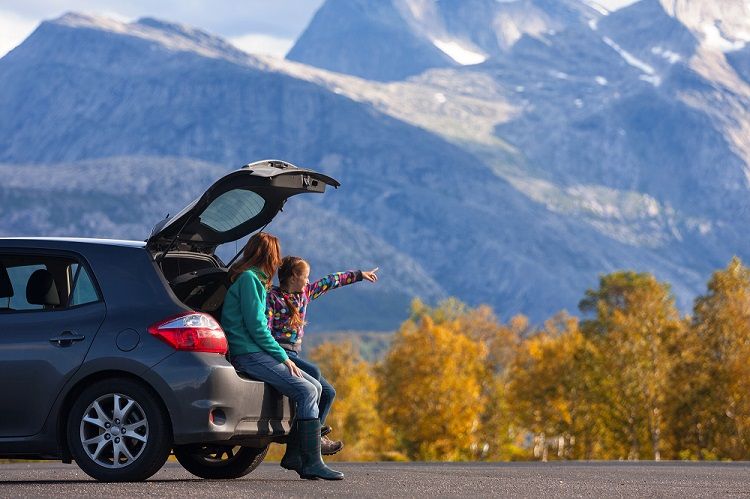 Mom and Daughter Sitting in the back of Car with Mountain Scenery