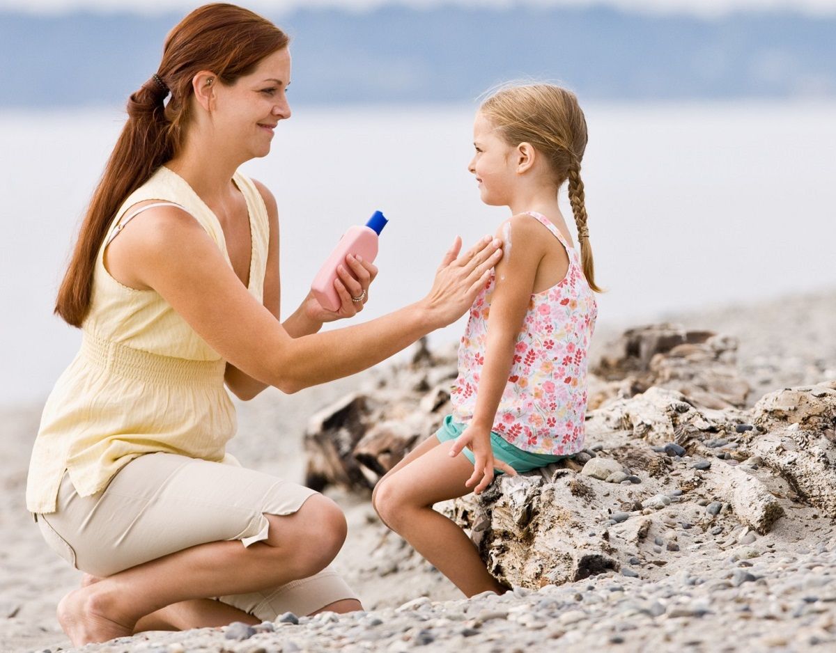 Mother applying sunscreen to her daughter on an Atlanta beach