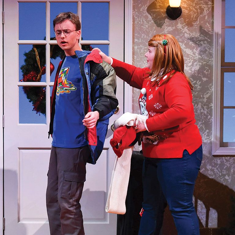 Berry alumna Katie Cooley helps fellow student take off his jacket in a Christmas play