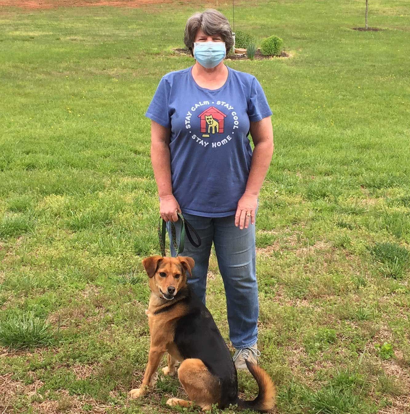 Berry alumna Bonnie Stevens stands outside while holding a dog on a leash.