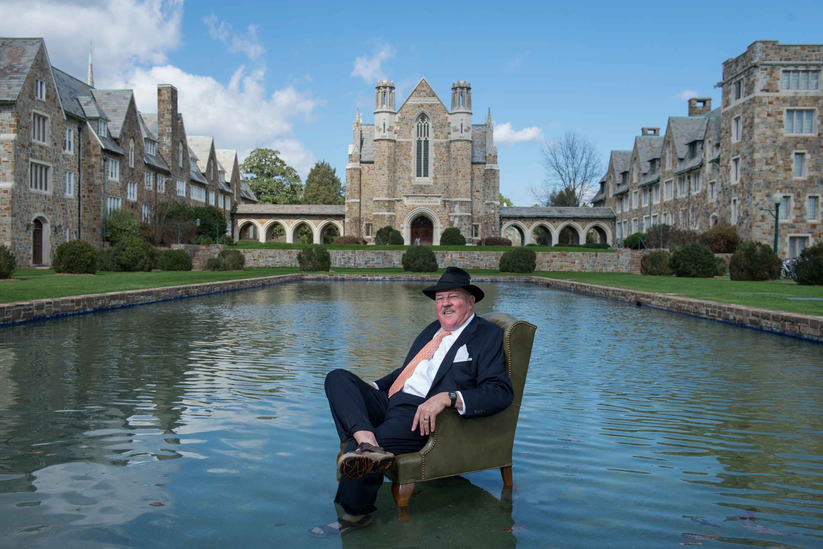 Berry alumnus sits in a chair in the reflecting pool in front of the Ford Buildings