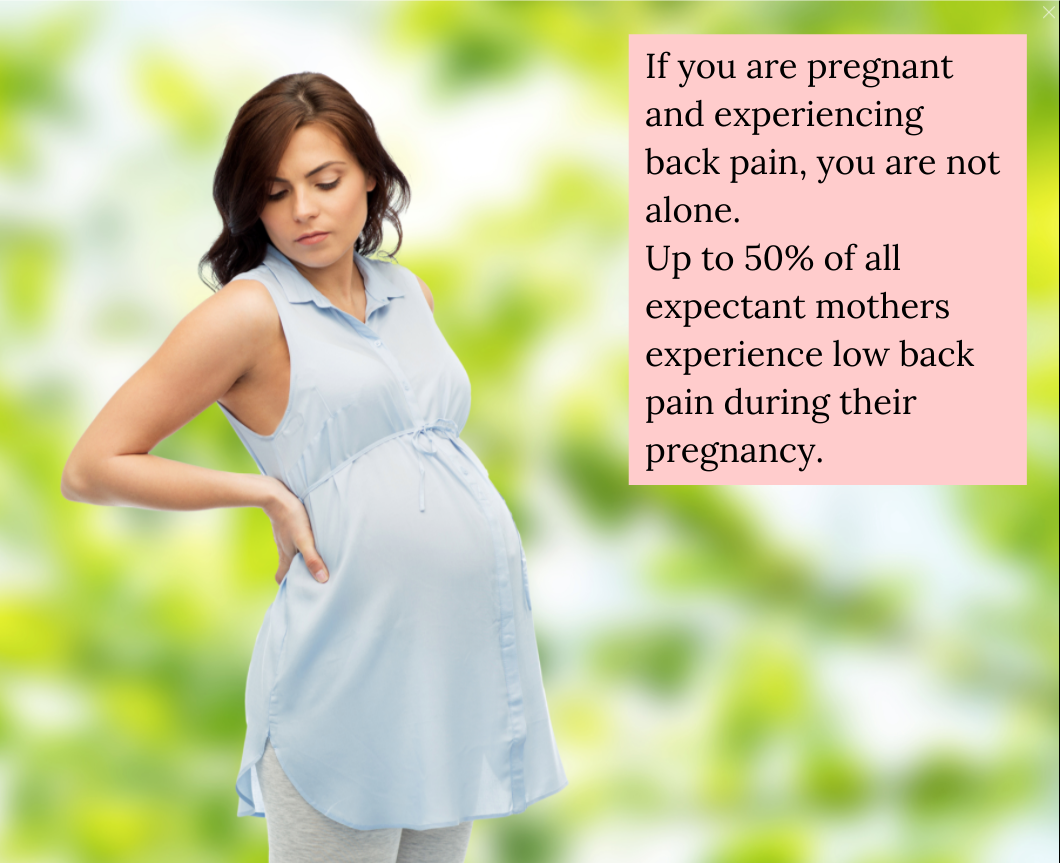A pregnant woman reaches for her lower back, in pain.