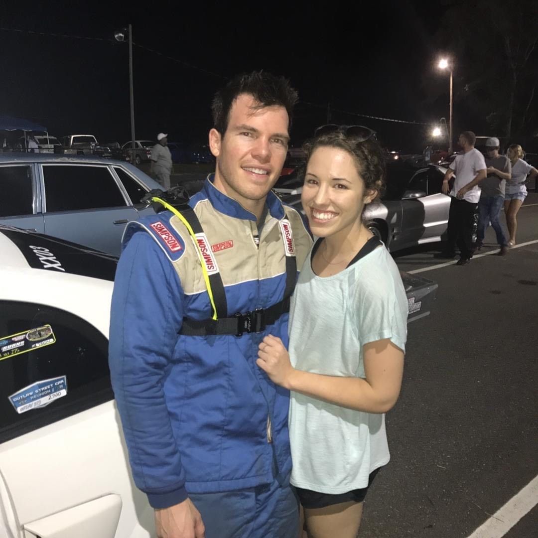 Dr. Jack Pines poses with a woman in front of his race car.