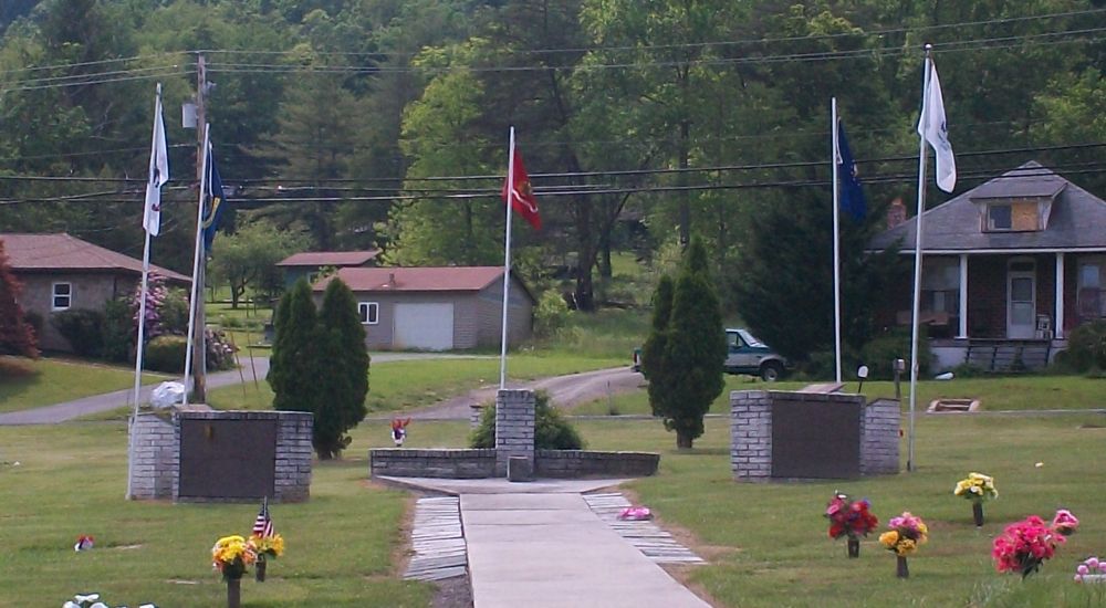 a path with flags and flowers on it and houses in the back