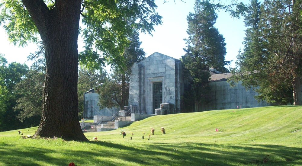 a large building with a lawn and trees in front of it