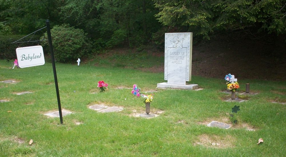 a grave with flowers and a sign