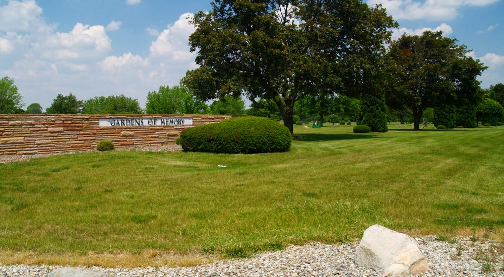 a grassy area with trees and a sign in the middle