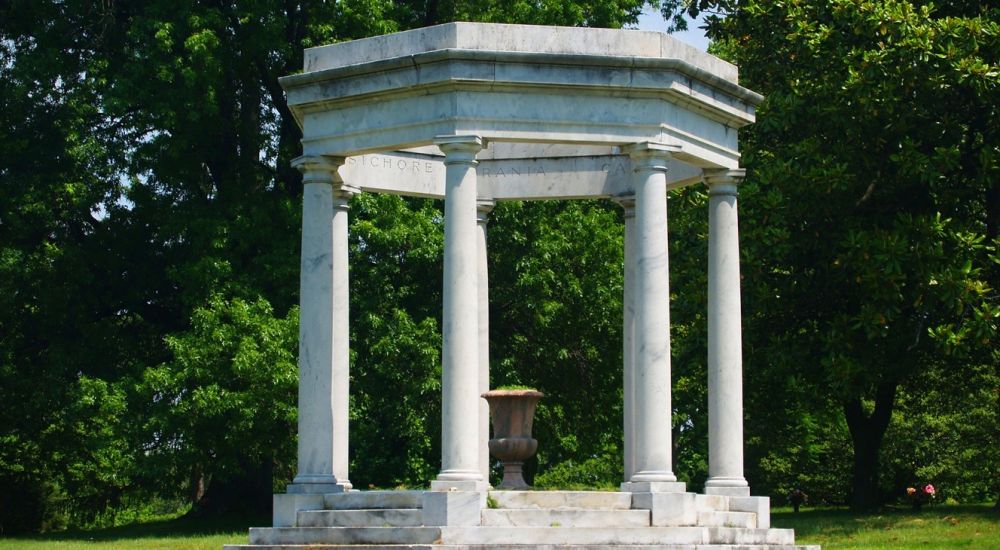 a stone structure with pillars in a park