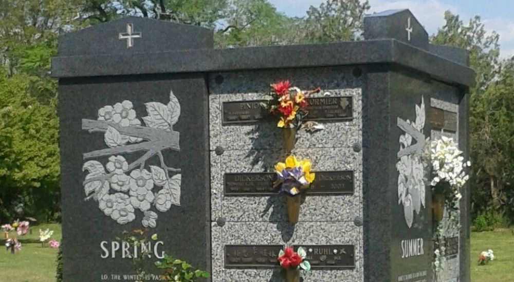 a tombstone with flowers and a cross