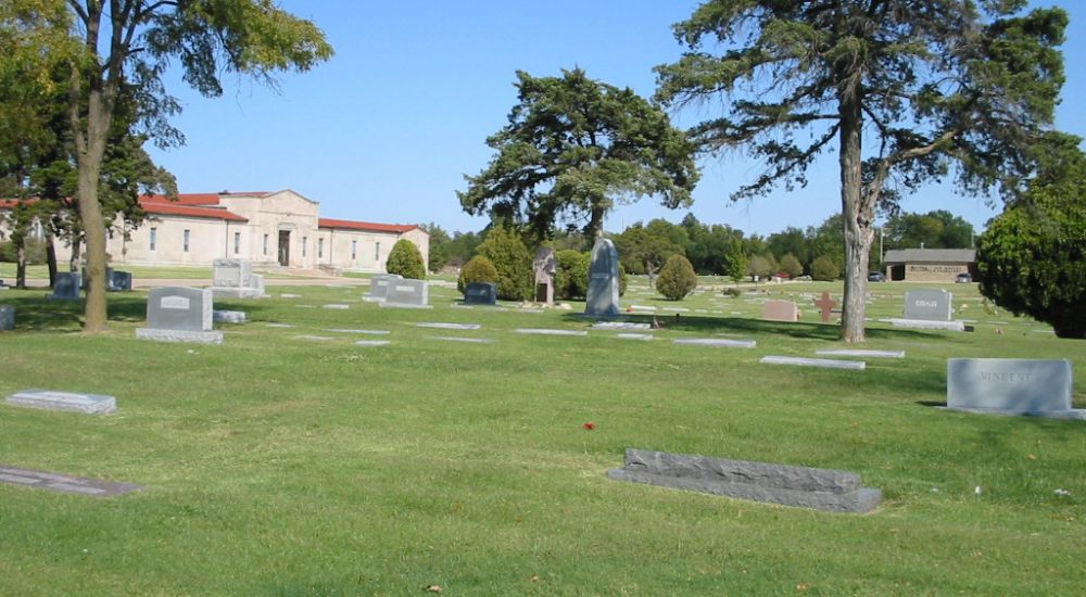 a cemetery with trees and a building in the background