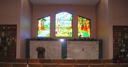 a room with chairs and a stage with stained glass windows