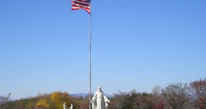 a flagpole with a statue in the middle of a park