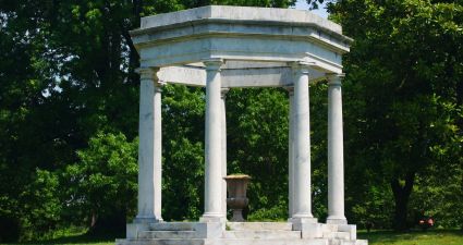 a stone structure with pillars in a park