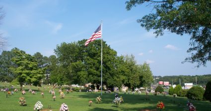 a flagpole with a flag on it in a park with people